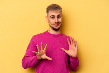 Young caucasian man isolated on yellow background rejecting someone showing a gesture of disgust.