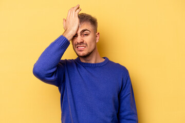 Young caucasian man isolated on yellow background forgetting something, slapping forehead with palm...