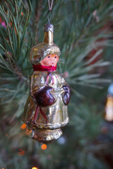 Vintage old glass Christmas toy boy in a sheepskin coat on pine branches close-up.