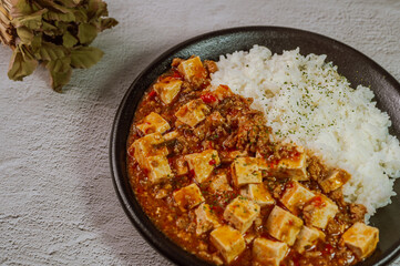 Chinese food mapo tofu dish and rice on black plate
