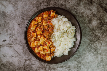 Chinese food mapo tofu dish and rice on black plate