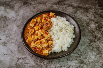 Chinese food mapo tofu dish and rice on black plate
