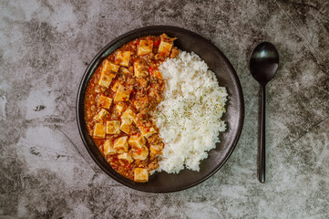 Chinese food mapo tofu dish and rice on black plate