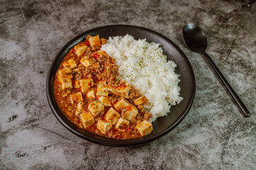 Chinese food mapo tofu dish and rice on black plate