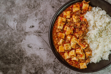 Chinese food mapo tofu dish and rice on black plate