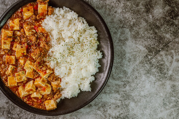 Chinese food mapo tofu dish and rice on black plate