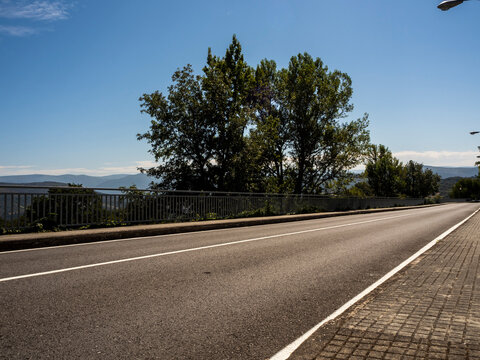 carretera asfaltada con barandillas en los laterales, la l&iacute;nea continua y un &aacute;rbol de fondo