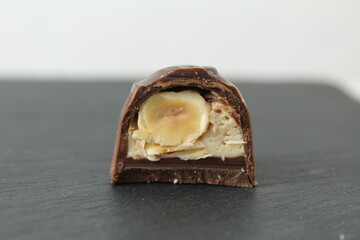 chocolate candy with praline white filling and hazelnut hazelnut in section. Dessert candy lies on a black black background with space for copyspace text. Chocolate Day. Chocolate case candy