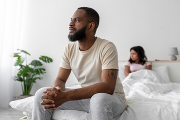 Sad millennial black man in domestic clothes ignores unhappy offended woman after quarrel