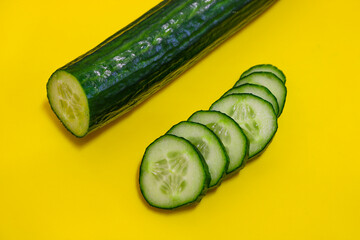 Cucumber cut into round pieces on a yellow background. The concept of vegetarianism and healthy food.