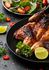 Roast Chicken Tabaka with salad, corn and lime on black plate.