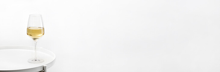 Banner of glass of white wine on a white round table. Minimalism. Elegant