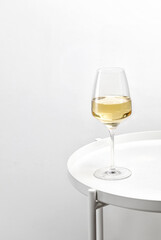 Glass of white wine on a white round table. Minimalism. Elegant
