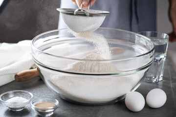Fototapeta na wymiar Sifting flour to make dough. Preparing flour to baking bread in kitchen at home.