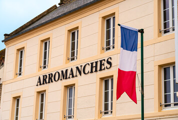 Fototapeta na wymiar Arromanches, France - August 2, 2021: Arromanches is remembered as a historic place of the Normandy landings - the city hall with the franch flag