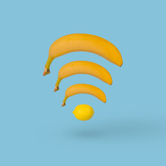 Creative Wi- Fi symbol isolated on blue background made of banana and lemon.