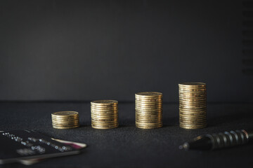 Stack of money coin on wood desk with calculator, credit card and pen. Business and financial concept