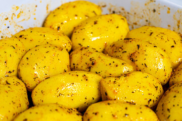 Raw potatoes with spices prepared for baking in oven