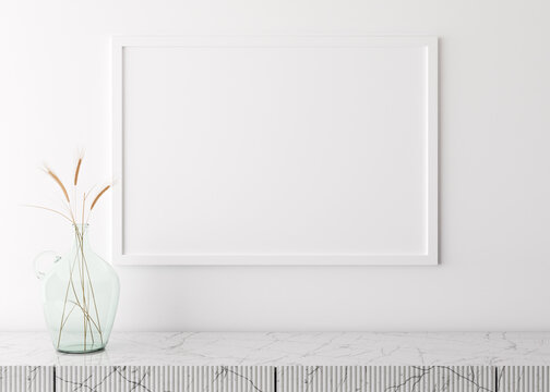 Empty picture frame on white wall in modern living room. Mock up interior in minimalist, scandinavian style. Free space for your picture. Marble console and dried grass in glass vase. 3D rendering.