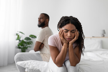 Sad offended millennial african american wife ignores upset husband after quarrel on bed