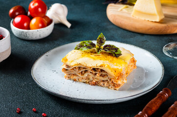 Piece of tasty hot lasagna on dark background. Traditional italian lasagna. Italian food. Close up lasagna. Bolognese sauce. Bechamel sauce. Still life of food. Homemade meat lasagna.