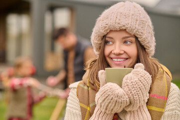 Woman in warm clothes with cup looking aside