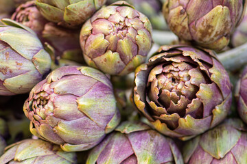 Fototapeta premium Fresh green artichokes with green leaves in a street food market, close up