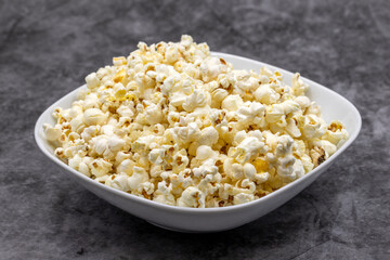 Popcorn on a dark background. Fresh popcorn in ceramic bowl. Close-up. Horizontal view