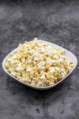 Popcorn on a dark background. Fresh popcorn in ceramic bowl. Close-up. Vertical view