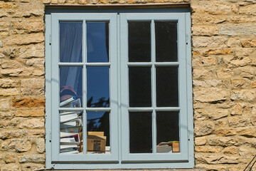 Grey window with books visible set in wall made of Cotswold stone
