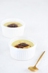 Vegan creme brulee in white bowls on a wooden table. Sugar, gluten and lactose free.
