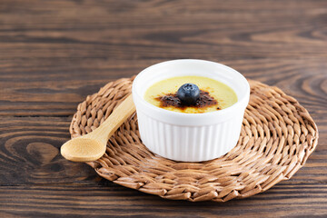 Homemade creme brulee with blueberries in a bowl on a wooden table. Sugar, gluten and lactose free and vegan.