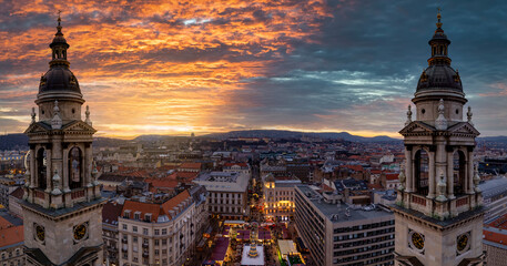 Fototapeta premium Panoramic view from the Saint Stephand Basilica to the skyline of Budapest, Hungary, with a christmas market at the square during a colorful winter sunset