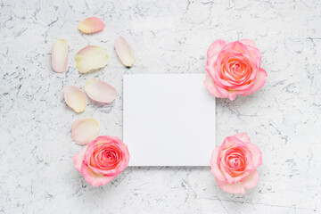 Empty card with pink roses and petals. Mockup invitation blank card. Template for branding and advertising. White concrete background, top view