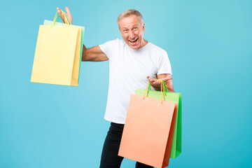 Excited mature man holding shopping bags at studio
