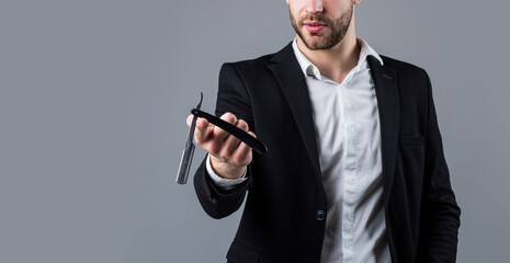Naklejka premium young handsome man in formal wear has bristle on face hold razor blade, barbershop