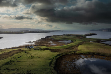 Aerial view of Isle of Skye with dramatic clouds and weather, a farm house on a small island surrounded by water