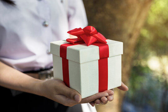 Woman holding gift box with red bow in hand
