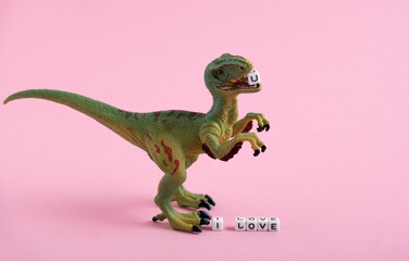 Cute dinosaur and the inscription I love you on a pink background. The dinosaur holds the letter U...