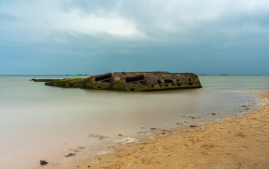 Fototapeta premium Arromanches, France - August 2, 2021: Remains of artificial military landing port in Arromanches in Normandy - long exposure