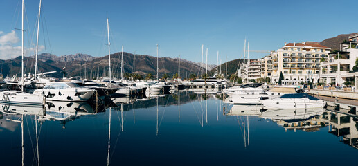 Fototapeta na wymiar Sailing yachts stand in a row at the pier against the backdrop of buildings