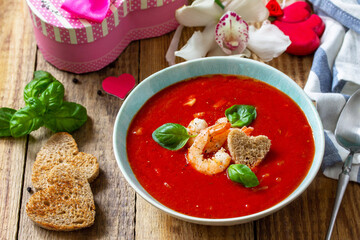 Homemade Valentine soup, festive food. Tomato soup puree gazpacho with tomatoes served seafood on a rustic wooden table.