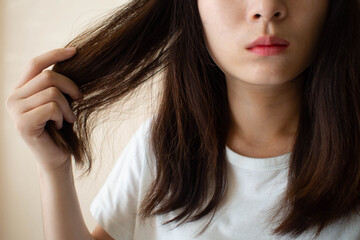 Young woman worried about dry hair, damaged hair and split ends. Hair problems and hair care concept. - obrazy, fototapety, plakaty