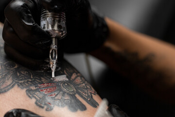 Close up of a tattoo artist's hand with black glove and his tattoo machine. Body art concept