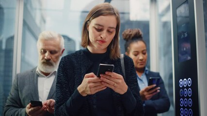 Three Diverse Multiethnic International People Ride a Glass Elevator to Office in a Modern Business Center. Focus on Young Beautiful Businesswoman Using Smartphone in a Lift.