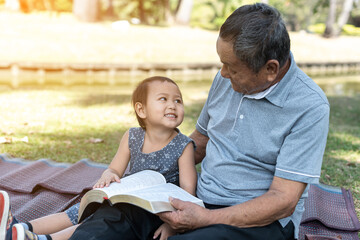 Asian elderly having faith to the Lord, God reading bible outdoor with kid