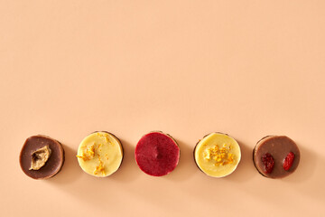 Colorful healthy raw vegan no-bake mini cheesecakes on pastel orange background