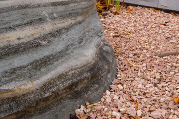 Natural monolith stone gray color in the garden. Coral color pebbles. Decorative stones for design.