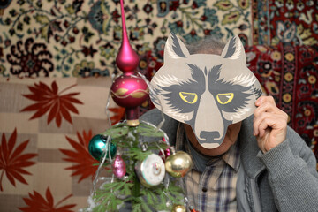 senior man with wolf mask near vintage christmas tree at home