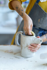 Professional sculptor girl creating ceramic tableware in studio. Young woman artist work with wet clay jug shaping handmade dishes. Creative craftswoman in workshop space. Pottery art hobby concept